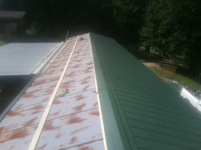 Old rusted panels beside newly installed green metal roofing — Wind Damage Roof Repair by Roofing Brothers in Island Park