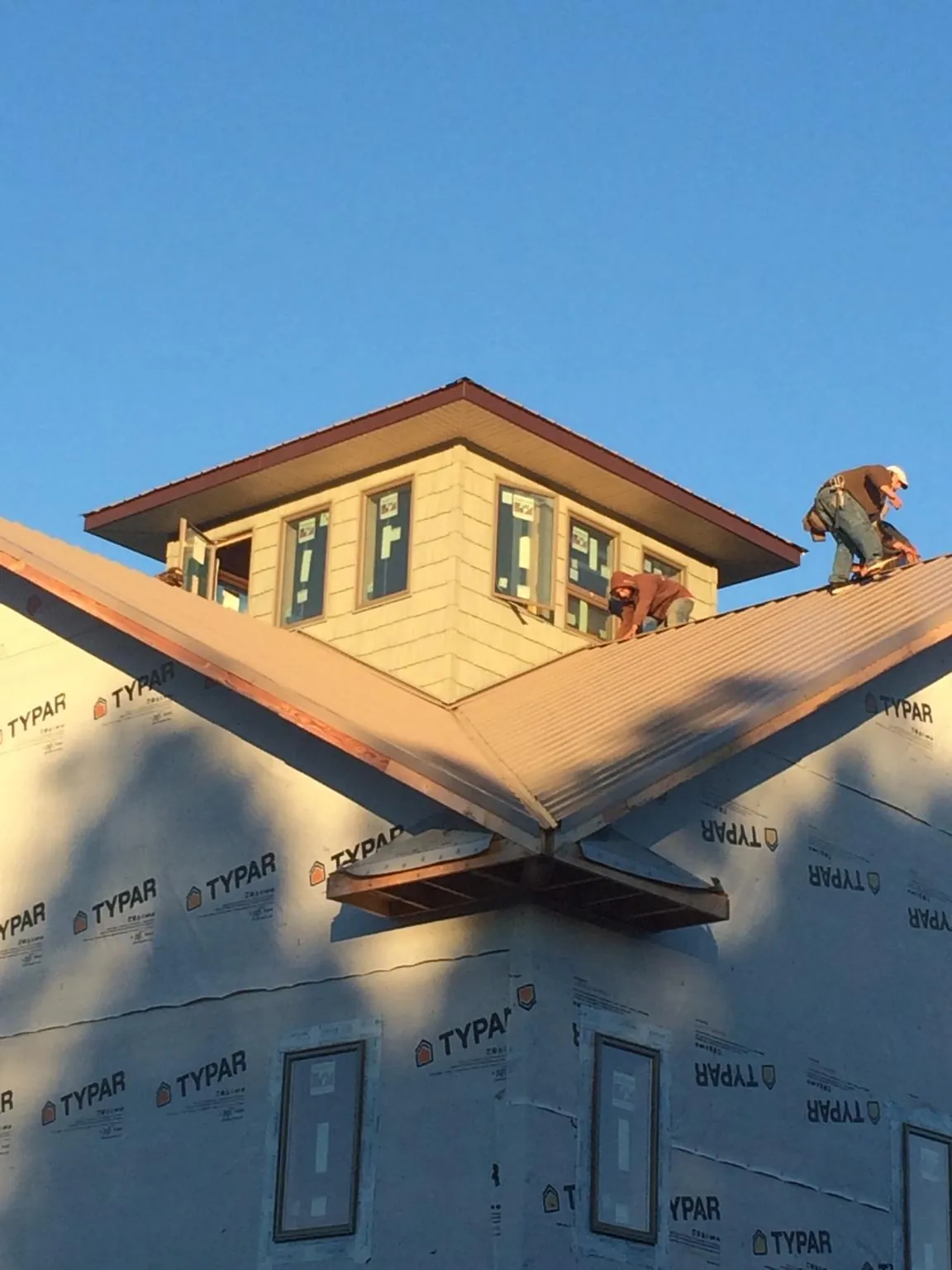 Roofers working around a rooftop cupola on a new metal roof at sunset — Roof Waterproofing in Island Park by Roofing Brothers